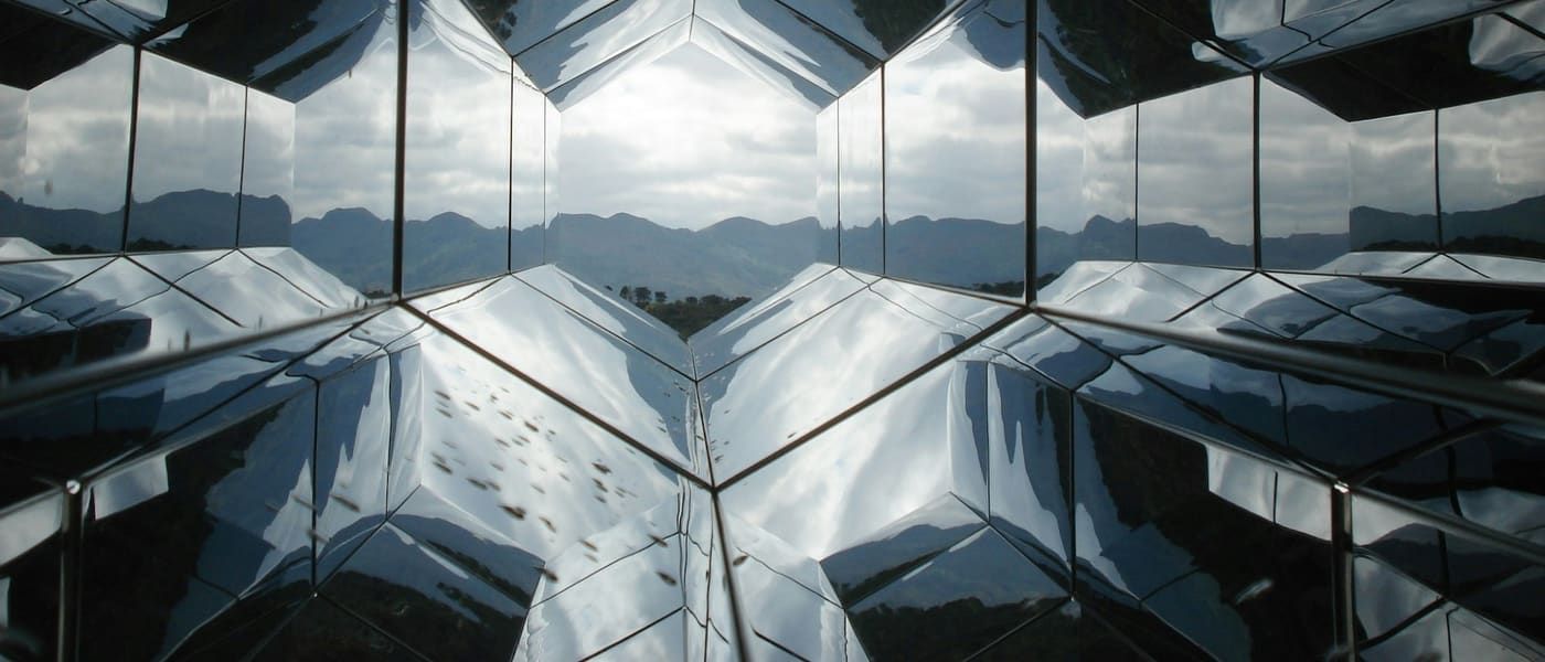 Abstract mirrored hexagonal structure reflecting a landscape